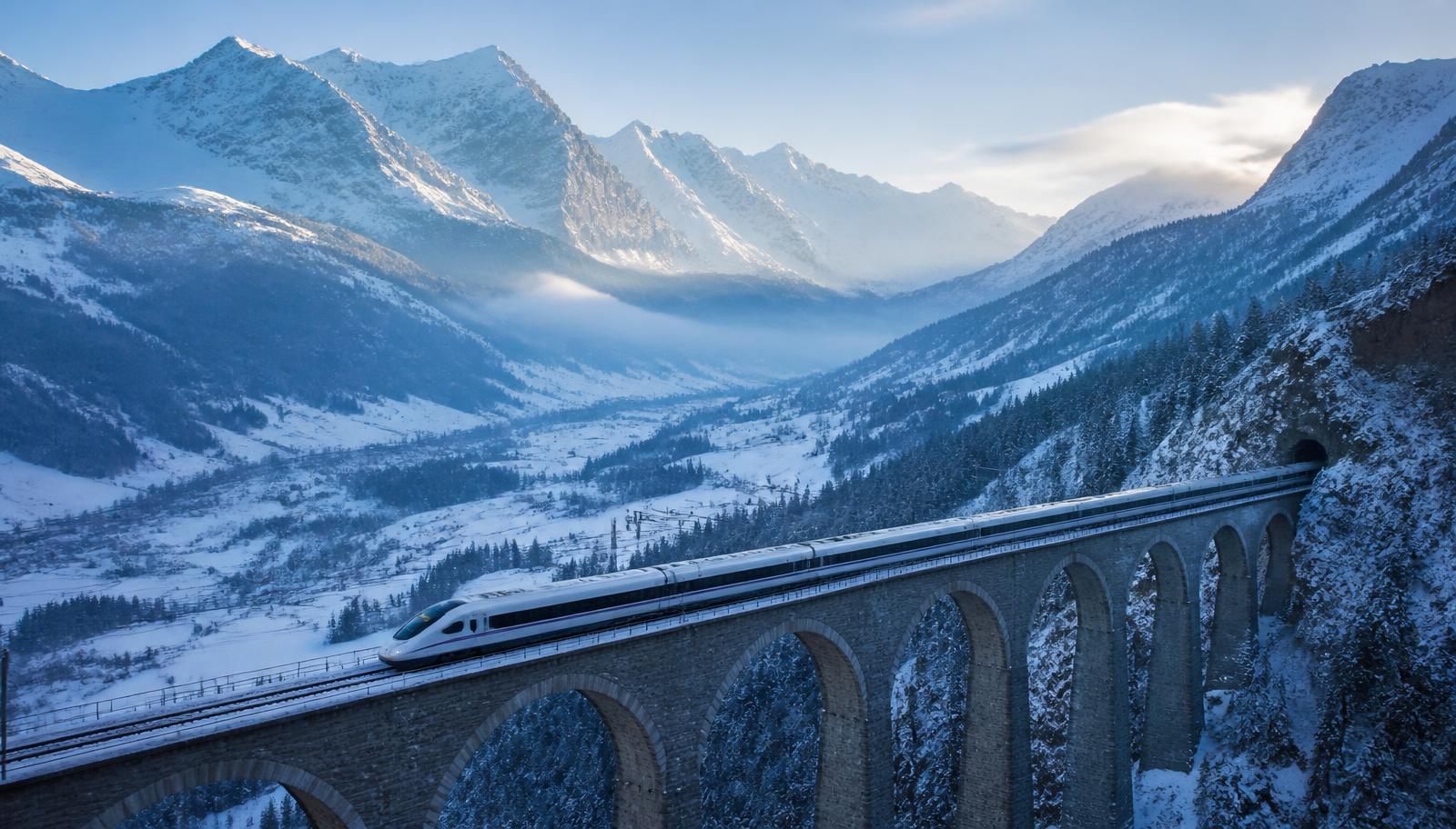 High-speed train crossing a snowy alpine viaduct